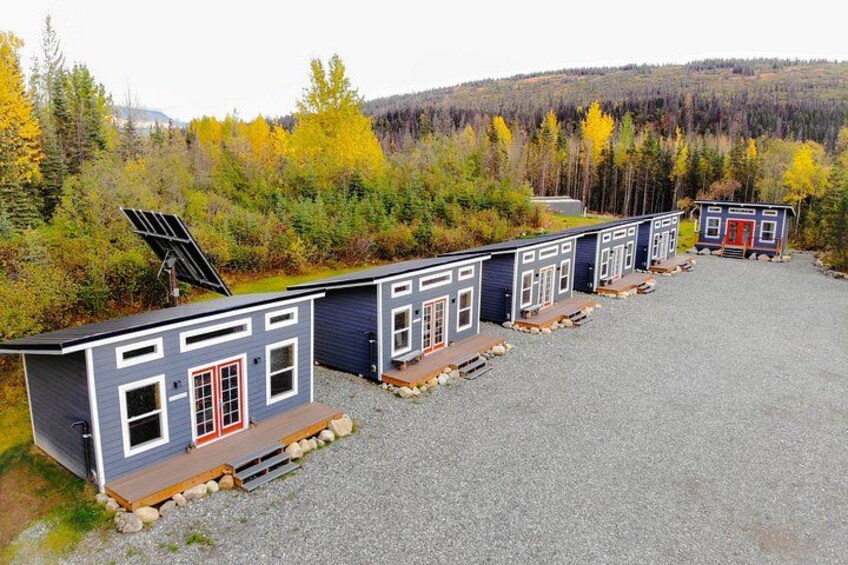 A row of cabins with solar panels, set against a forest backdrop. 4
