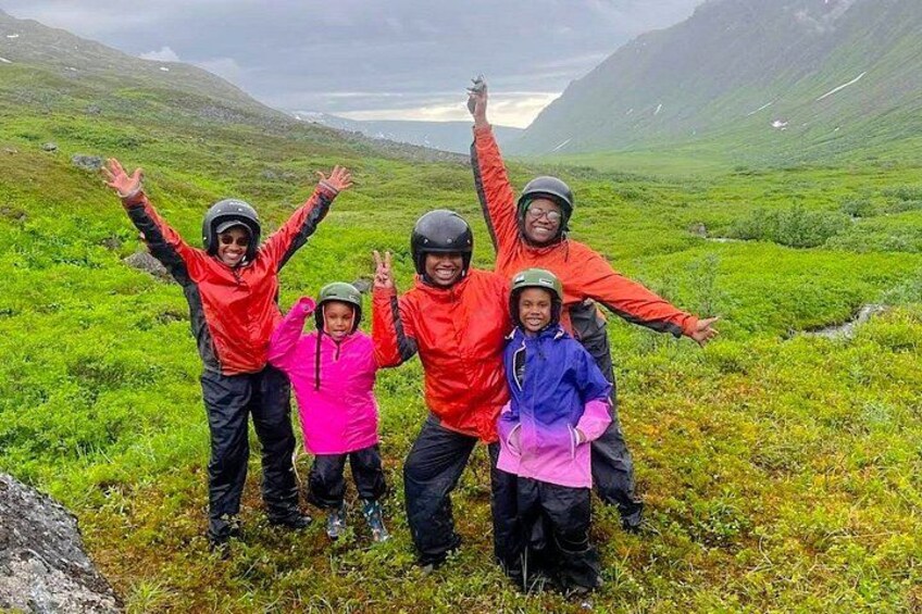 A group of people in a mountainous landscape with greenery and a lake in the background. 3