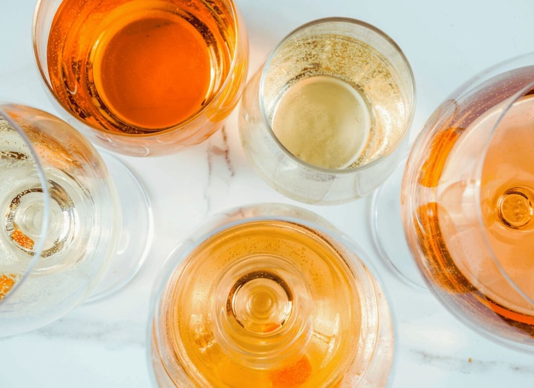 Four glasses of different colored liquids on a marble surface. 3