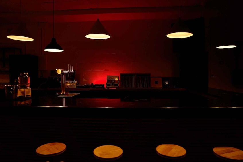 A dimly lit bar with wooden stools and pendant lights. 5