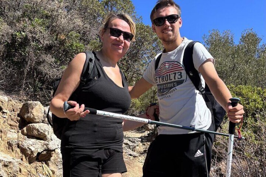 Two people hiking with trekking poles in a rocky, hilly terrain. 5