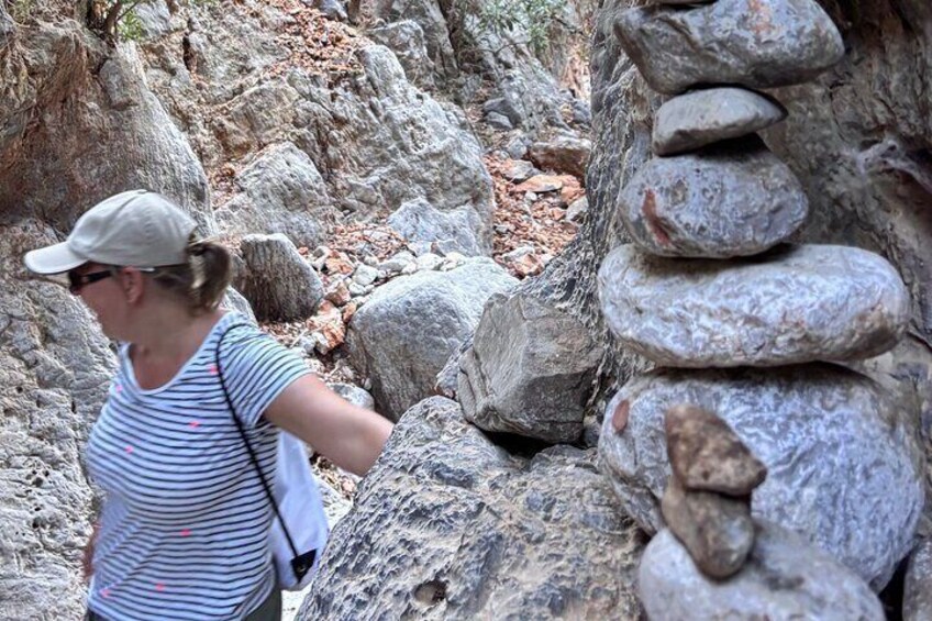 A person walking near a stack of rocks in a rocky terrain. 3