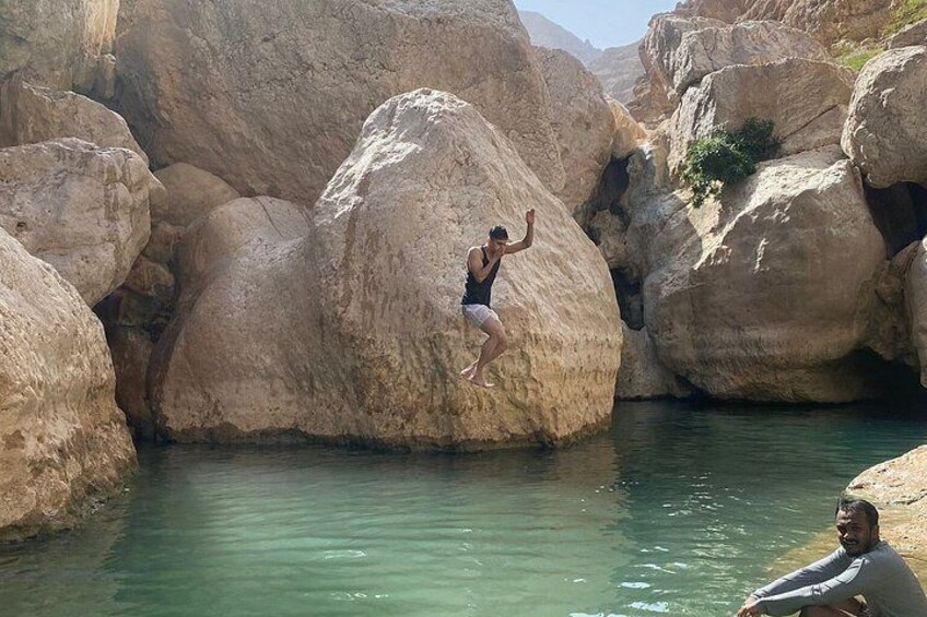 A person climbing a large rock formation by a body of water. 4