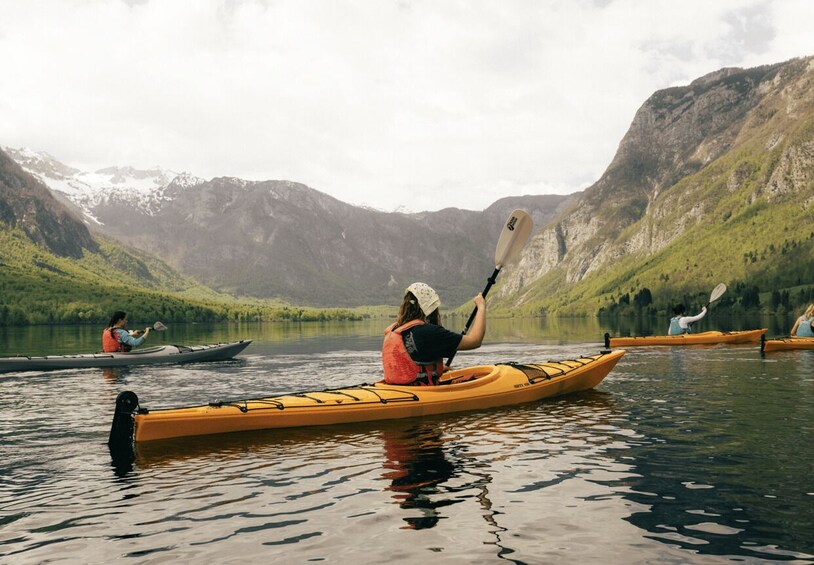 A person kayaking on a calm lake surrounded by mountains. 4