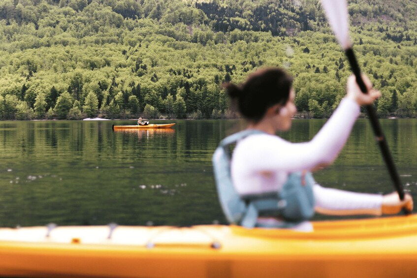 A person kayaking on a calm lake with dense forest in the background. 3