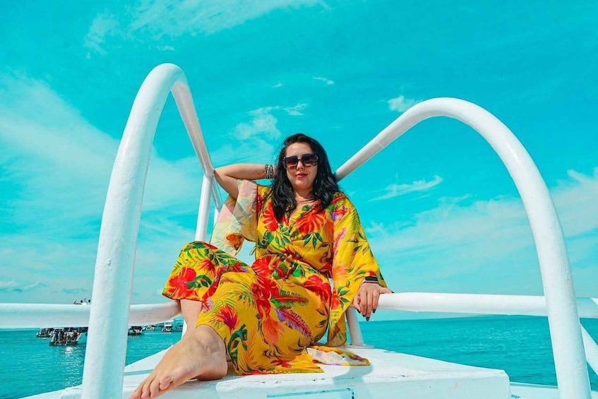 A person sitting on a boat deck with a clear blue sky and calm sea in the background. 4