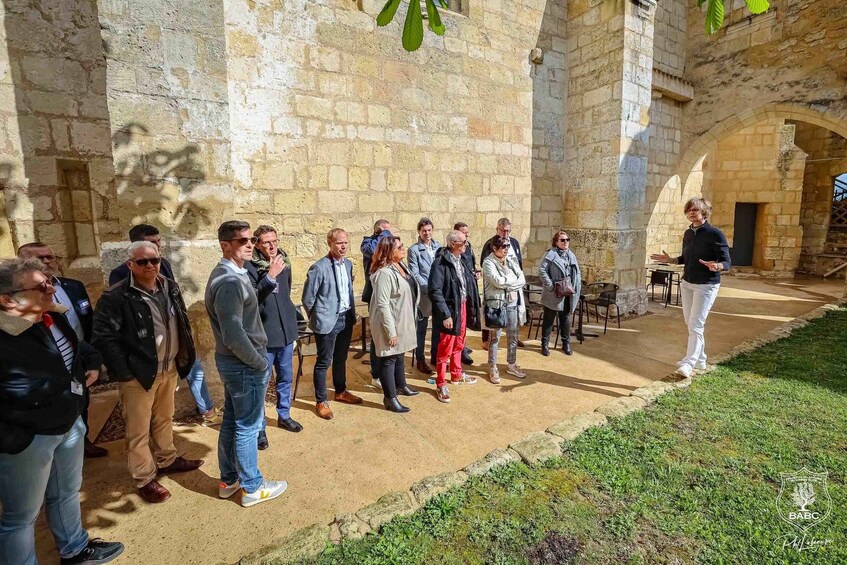 A group of people standing in an outdoor courtyard with stone walls and a grassy area. 5