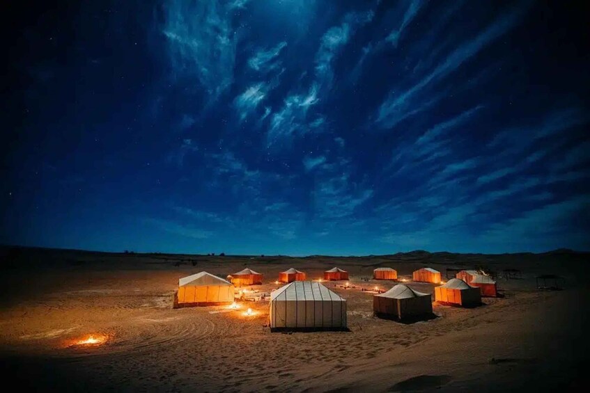 A desert landscape at night with multiple yurts illuminated by artificial lights. 5