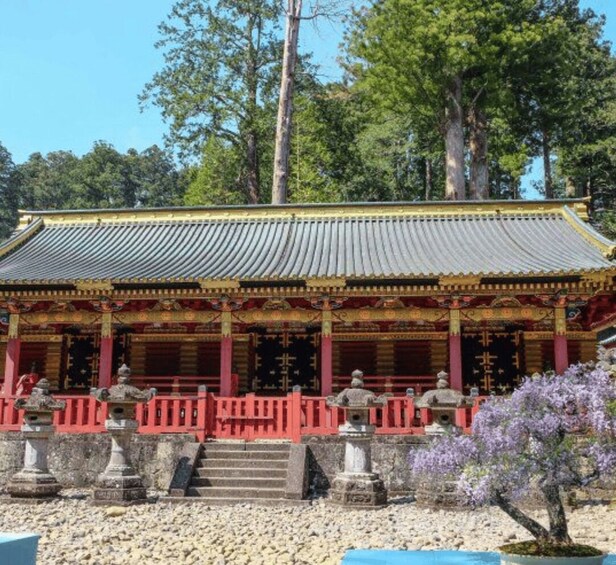 A traditional building with a tiled roof, red columns, and statues in front. 4
