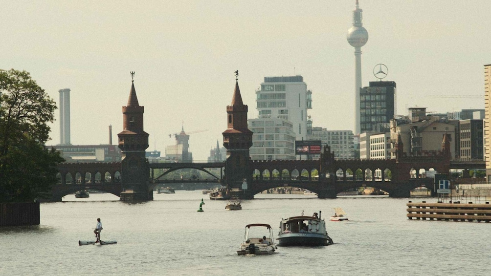 A river with boats, a bridge, and a tower in the background. 1