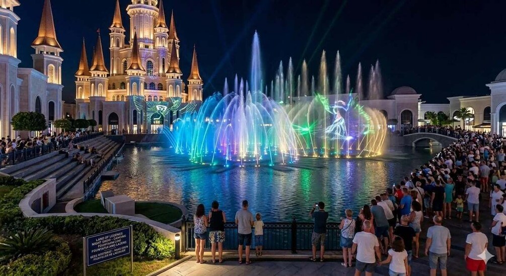A castle with a water fountain display and a crowd of people. 3