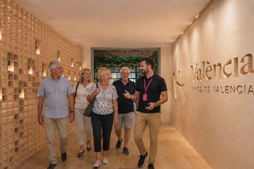 A group of people walking in a hallway with a wall displaying the text 'Valencia.' 5