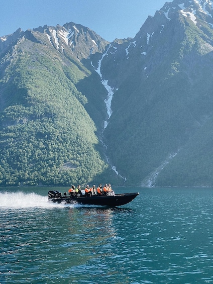 A boat speeding across a calm lake with a mountainous backdrop. 2