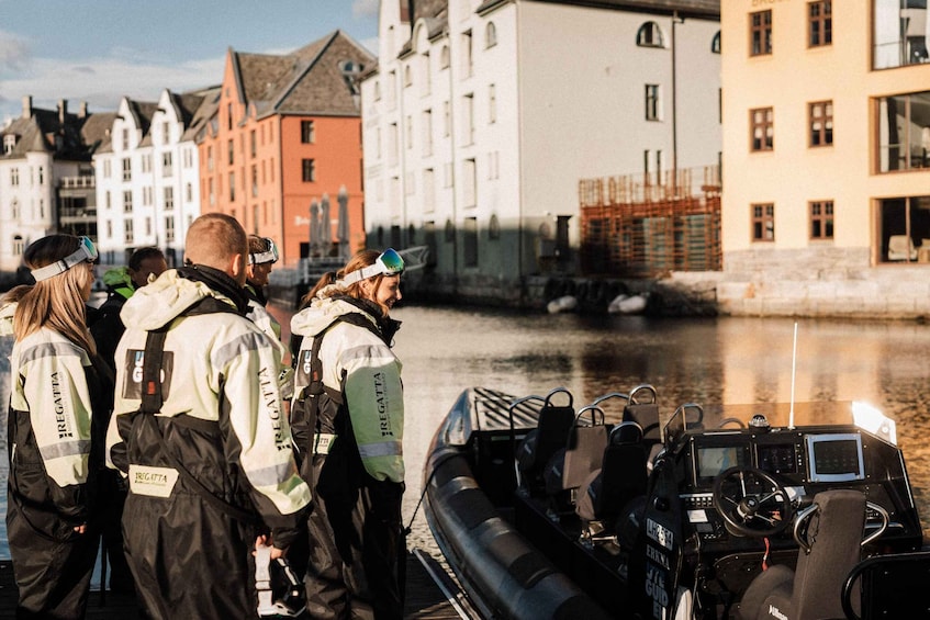 A group of people in reflective jackets by a river, with a boat and historic buildings in the background. 3