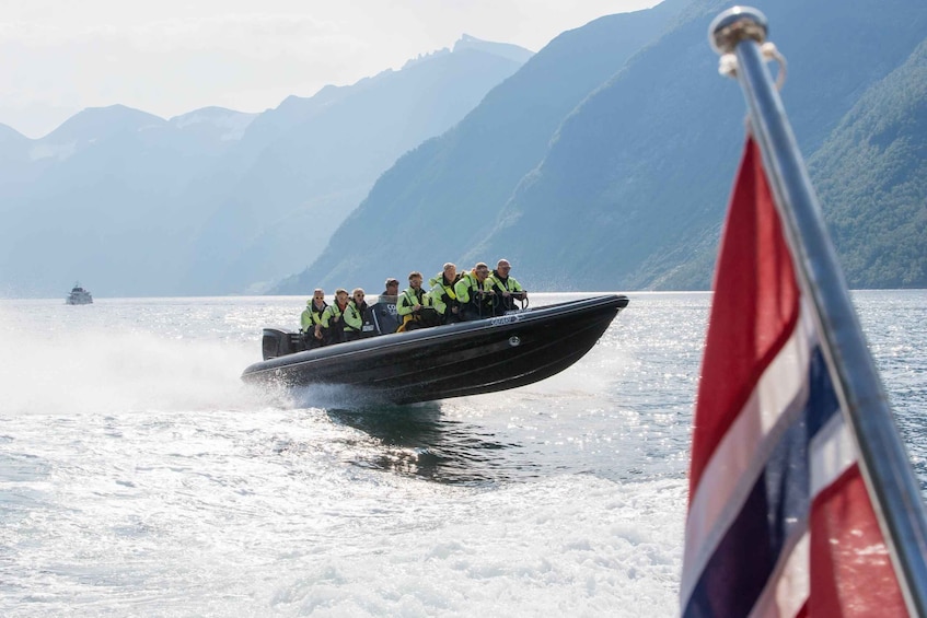 A boat with people wearing safety vests on a lake with mountains in the background. 1
