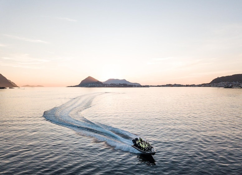 A speedboat creating a wake in calm waters with mountains in the background. 4