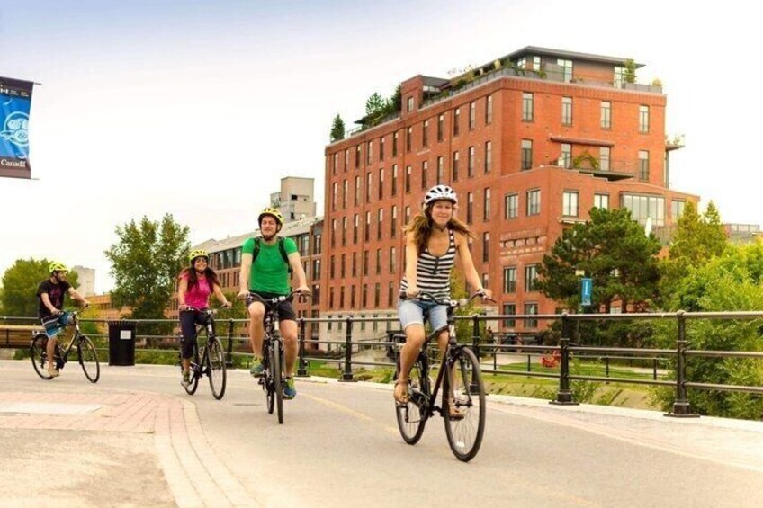 A group of people riding bicycles on a paved path with a brick building in the background. 5