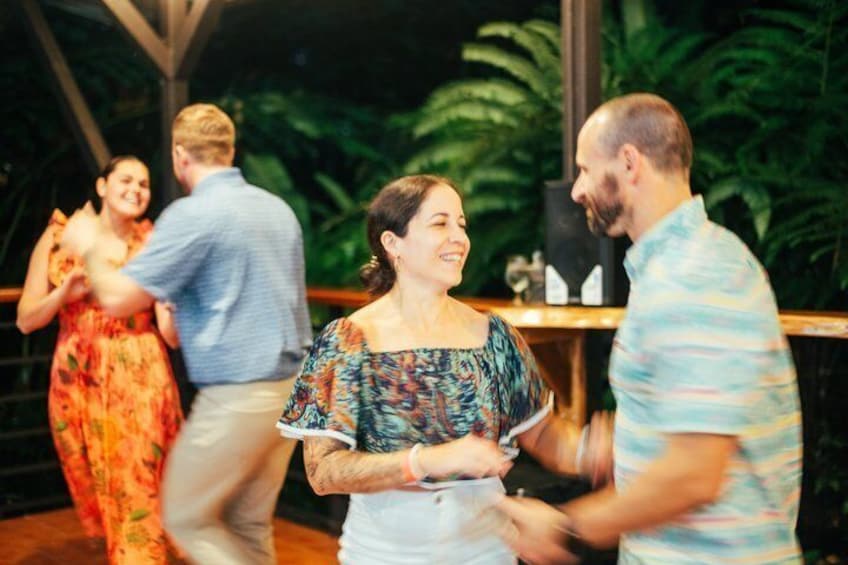 People dancing in an indoor setting with tropical plants in the background. 5