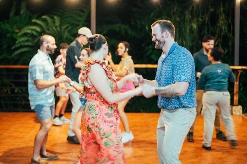 People dancing on a wooden floor with a tropical backdrop. 3