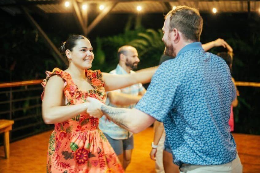 A couple dancing at an outdoor event with a wooden floor and a metal railing in the background. 2