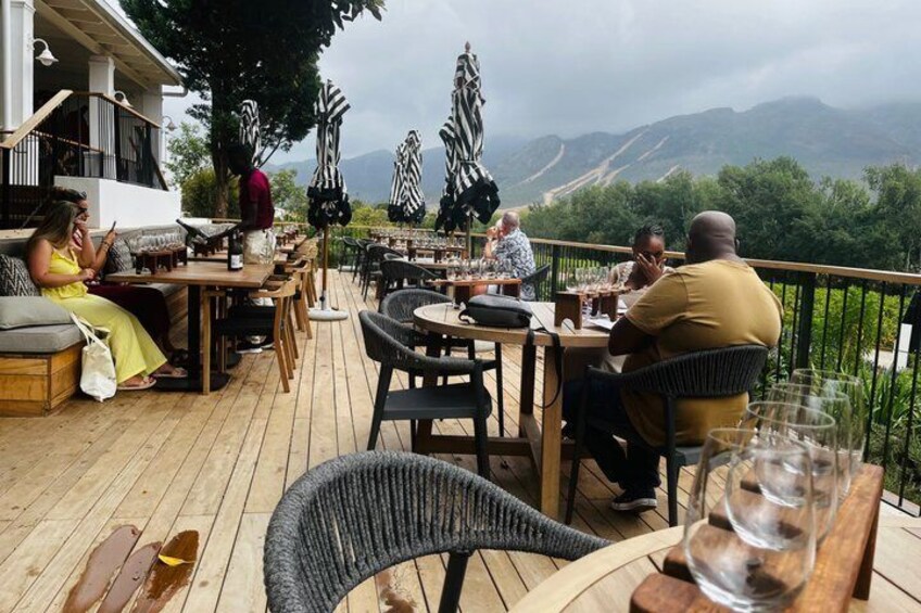 An outdoor patio with tables and chairs, overlooking a mountainous landscape. 2