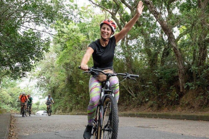A person riding a bicycle on a road surrounded by trees. 3