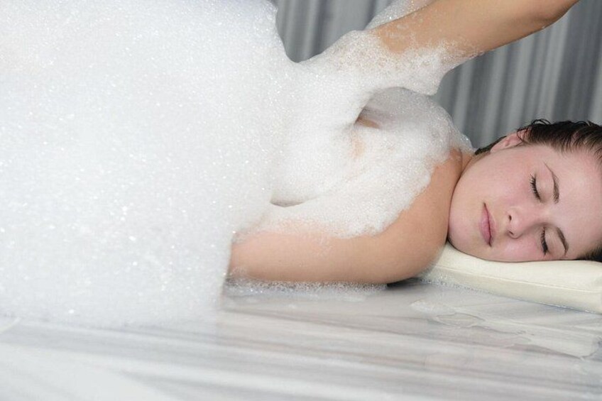 A person lying on a bed covered in white foam. 2