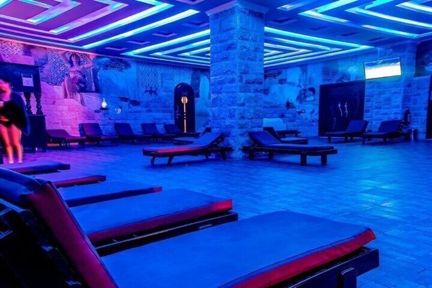 A spa with stone walls, blue lighting, and sun loungers. 2