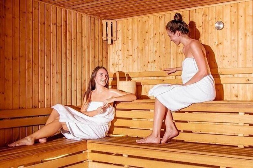 Two people in a sauna with wooden benches and walls. 5