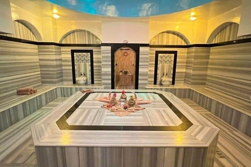 A spa with a large marble pool, arched doorways, and striped walls. 3