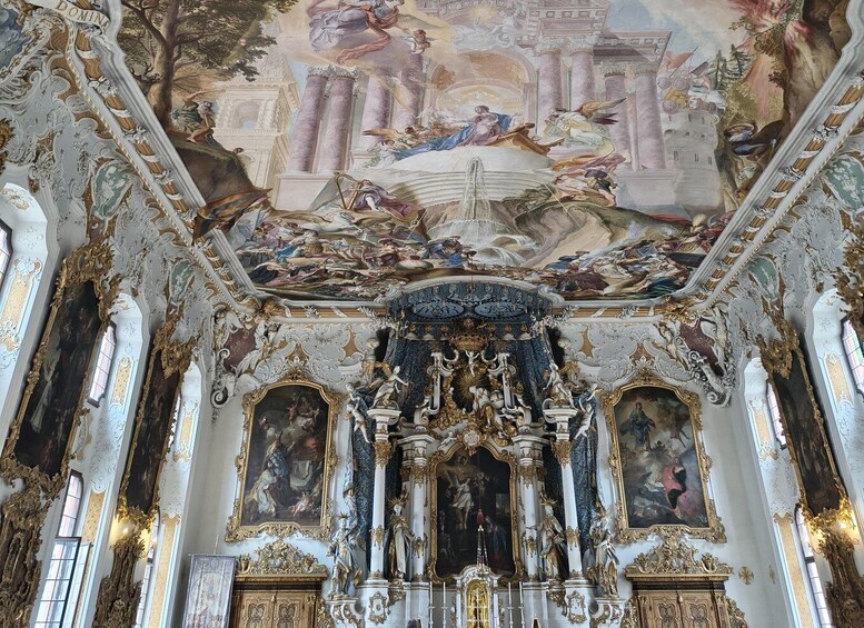 An ornate church interior with elaborate frescoes, gilded columns, and a central altar. 3