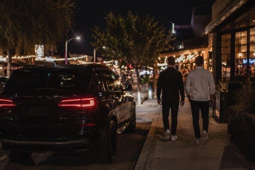A dark street with a parked car and two people walking. 2