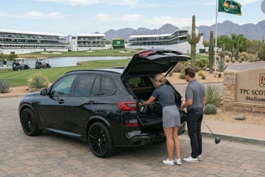 A golf course with a black SUV parked, a tee box, and a sign for TPC Scottsdale Stadium. 3