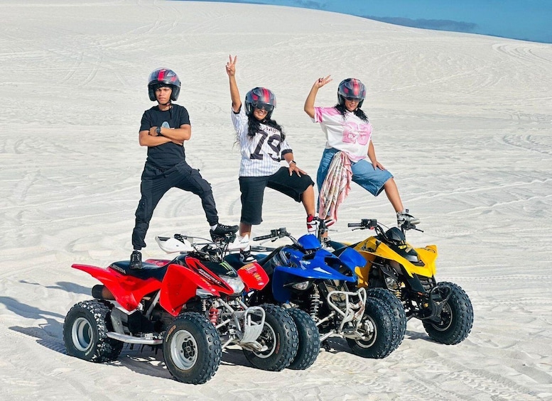 Three people on quad bikes in a snowy landscape. 5