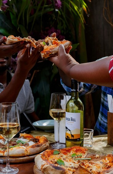 A table with pizzas, wine glasses, and a bottle of wine. 3