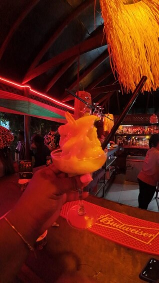 A person holding a large, fluffy dessert with a glass on a table with a 'Budweiser' logo. 4