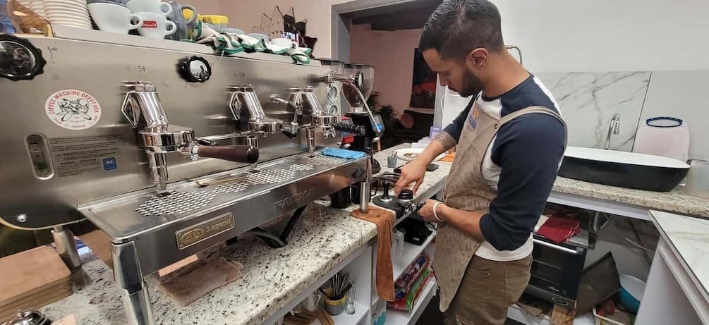 A person operating a commercial espresso machine in a kitchen. 2
