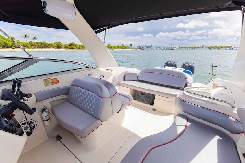 A boat's interior with cushioned seating and a steering wheel. 4