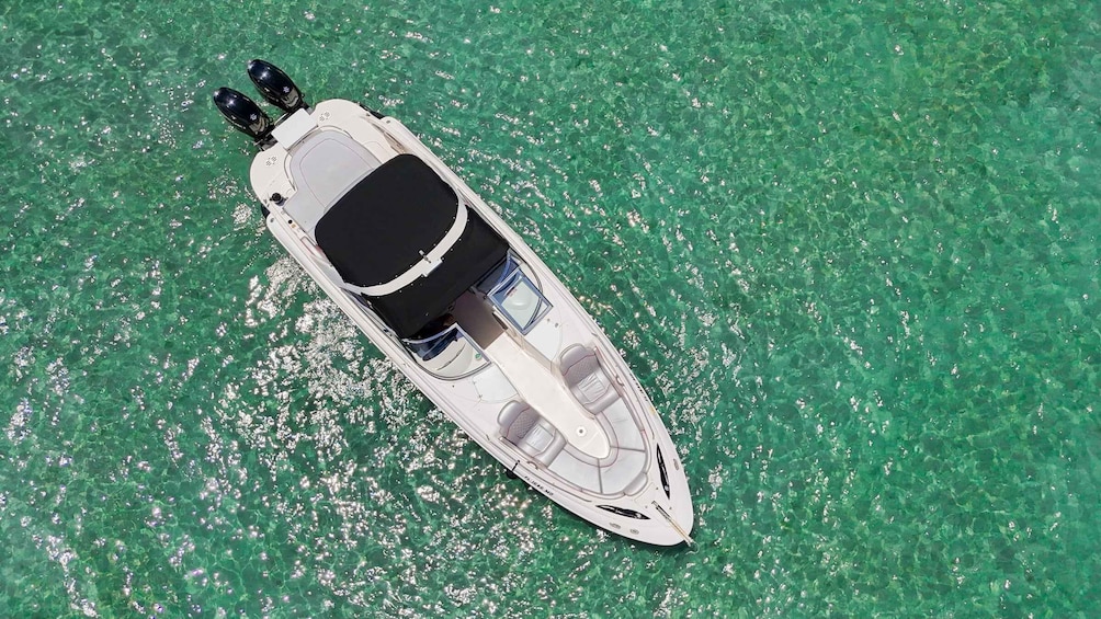 A white motorboat with a black canopy on a clear turquoise sea. 5