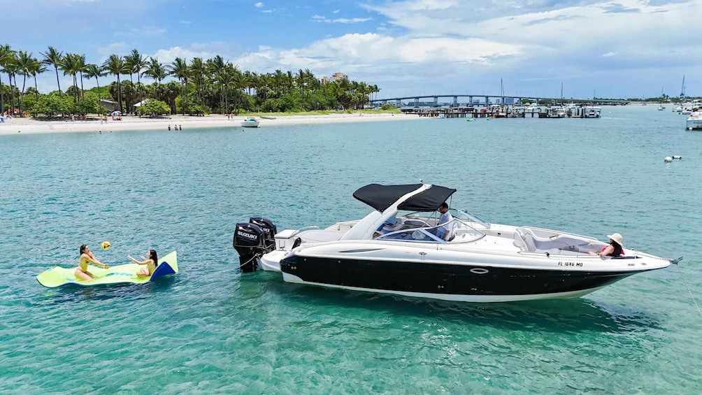 A boat on clear turquoise water with a beach and palm trees in the background. 2