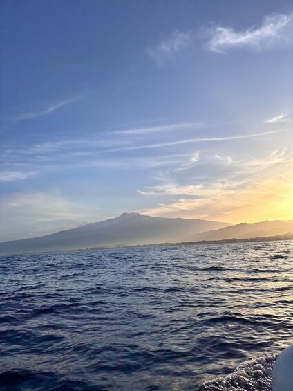 A body of water with waves, a mountain in the distance, and a clear sky. 2