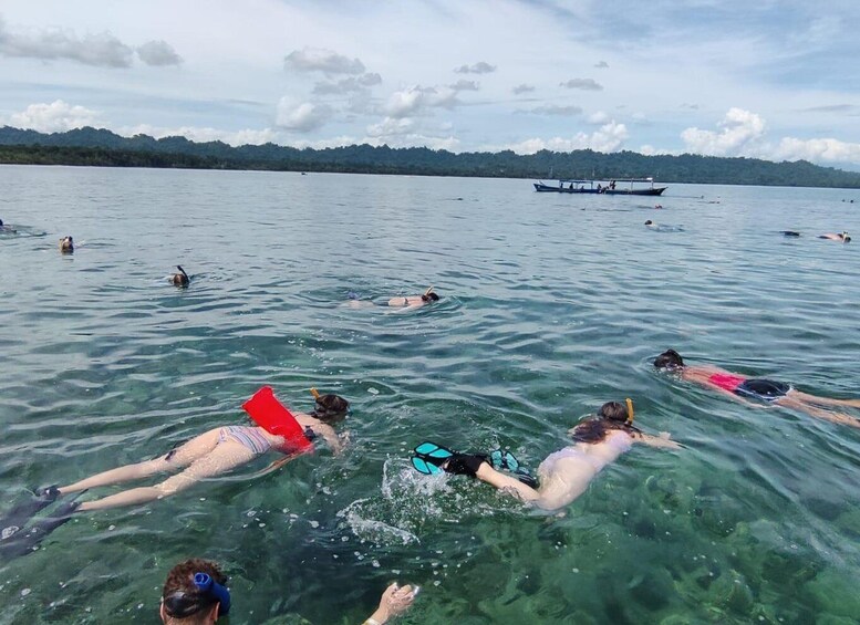 People swimming in a lake with a boat in the background. 1
