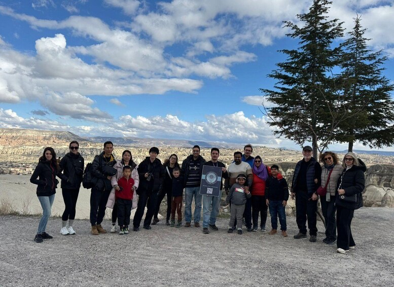 A group of people standing on a gravel path with a mountainous landscape in the background. 2