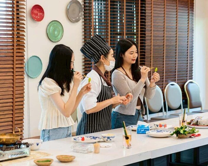A group of people cooking in a modern kitchen with wooden blinds and colorful plates. 4