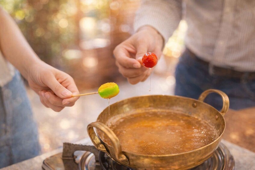 A person dipping a green and red object into a pan of liquid. 5
