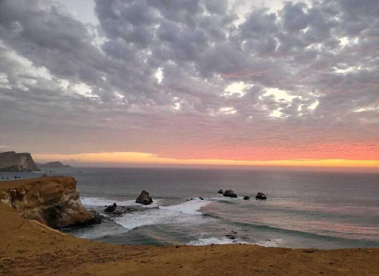 A coastal landscape with a rocky shoreline, waves, and a sunset sky. 3