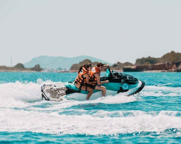 Two people on a jet ski in turquoise water with a mountainous landscape in the background. 3