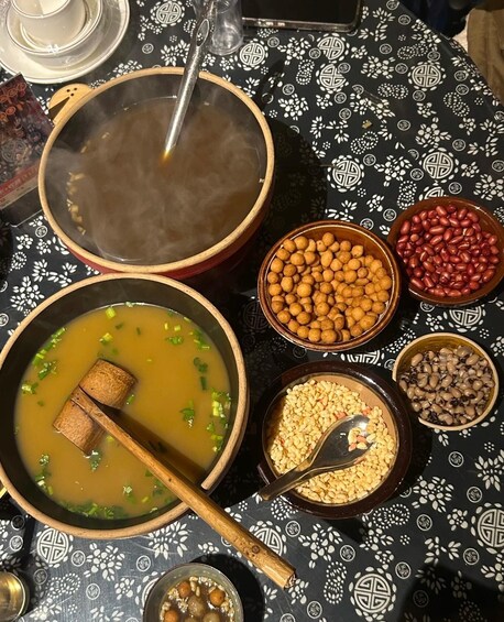 A table with various food items including a pot of soup, bowls of beans, and other dishes. 3