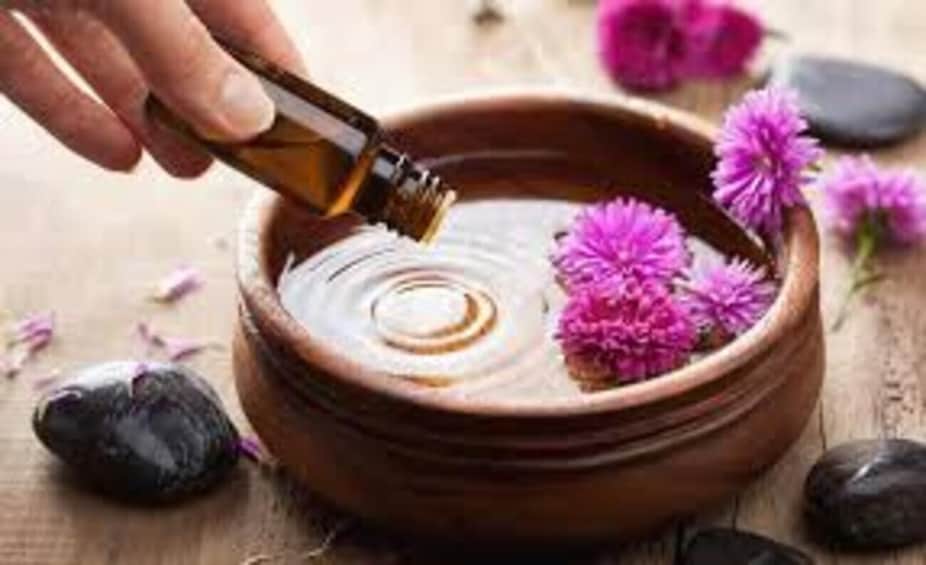 A hand pouring liquid into a bowl with flowers. 3