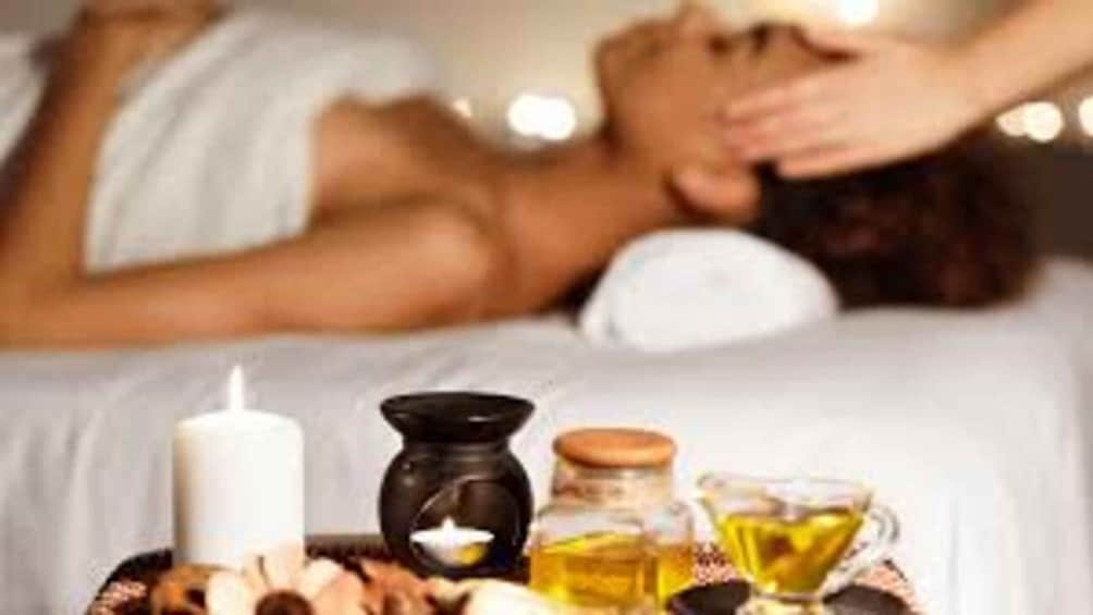 A spa setting with a candle, essential oils, and a massage. 2